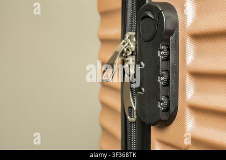 A close-up shot of a three-digit built-in combination lock on a modern beige or brown travel suitcase. Stock Photo