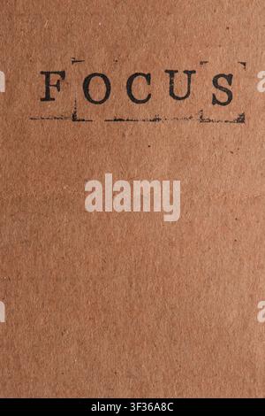 Vertical orientation word FOCUS stamped in black ink at top brown craft paper background Stock Photo