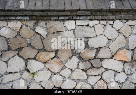 This high-resolution texture showcases an aged grey brick wall with rough, uneven surfaces and visible weathered cement mortar between each block. The Stock Photo