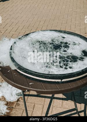 Close-up of an outdoor wash basin overflowing with soap bubbles during cleaning. Bright daylight, abundant foam, and textured surfaces create a fresh Stock Photo