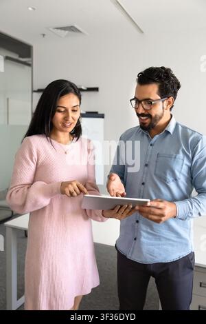 Multiethnic coworkers reviewing business information on digital tablet Stock Photo