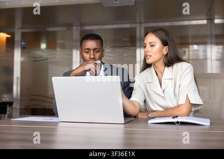Diverse colleagues discussing business data on laptop in office Stock Photo