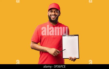 Delivery Man Holding Folder With Blank Paper Over Yellow Background Stock Photo