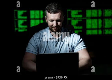 Programmer uses laptop for coding work. Programmer analyzes code screen with concentration. Programmer monitors network and firewall system Stock Photo