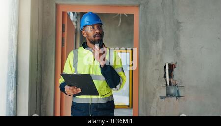 Construction, man or clipboard with site radio for building safety, electrical evaluation or report. Inspector, black person and talking on tech for Stock Photo