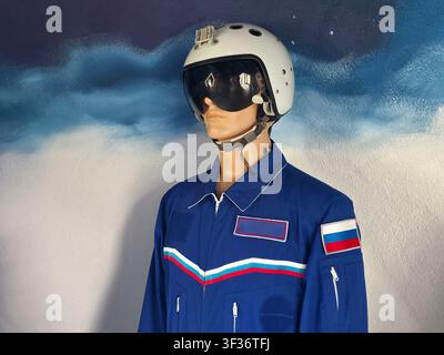 Close up view of mannequin wearing aviator uniform. Blue flight suit features red, white, blue stripes, and patches. White helmet has dark visor and c Stock Photo