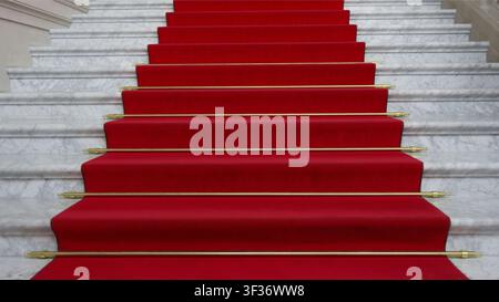 Elegant staircase with a luxurious red carpet and white marble steps Stock Photo