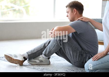 Young woman supporting man with suicidal thoughts at home Stock Photo