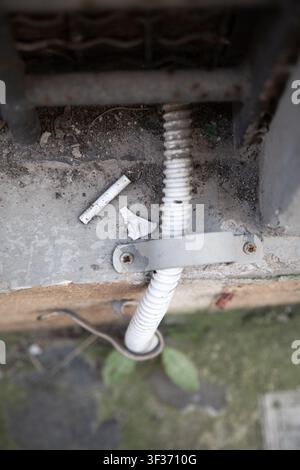 corroded metal spring exposed on abandoned concrete surface top-down perspective gray and white background clean construction repair maintenance Stock Photo