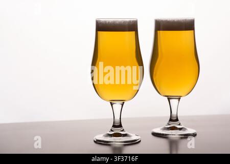 Two glasses of light beer with foam on table and on white background Stock Photo