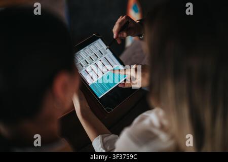 Colleagues reviewing financial data on a tablet during remote work meeting in a casual setting Stock Photo