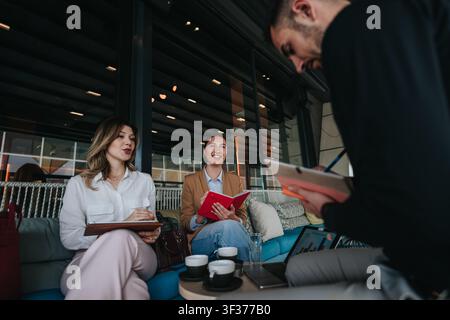 Colleagues meeting casually on a sofa during remote work session with notebooks and coffee Stock Photo