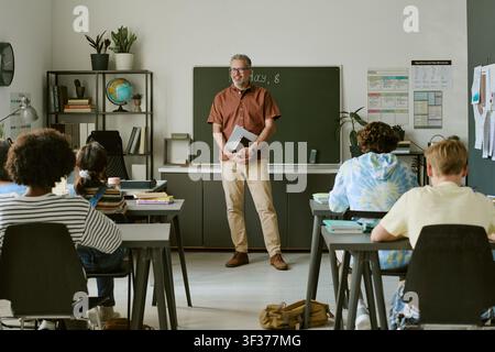 Diverse Teen Students Studying in Classroom with Male Teacher Stock Photo