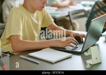 Teen Boy Studying on Laptop in Classroom for Digital Learning Stock Photo