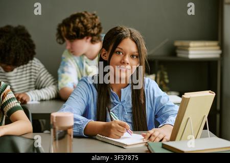 Portrait of Biracial Teen Girl Studying in Classroom Stock Photo