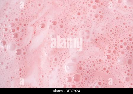 Pink milkshake texture closeup. Strawberry milk shake foam background, fruit smoothie bubbles macro photo, whipped milky frothy cocktail top view Stock Photo