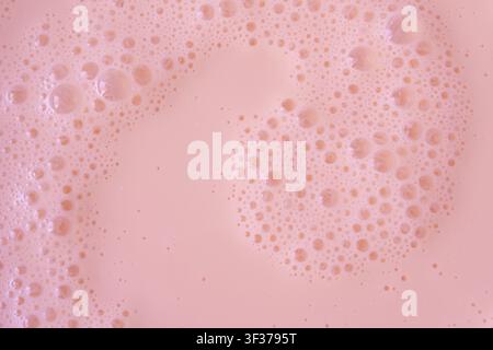 Pink milkshake texture closeup. Strawberry milk shake foam background, fruit smoothie bubbles macro photo, whipped milky frothy cocktail top view Stock Photo