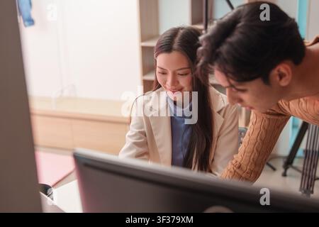 Asian creative professionals collaborating and reviewing project on computer screen Stock Photo