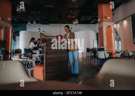 Smiling host woman welcoming colleagues in modern coworking cafe during remote work and casual meeting Stock Photo