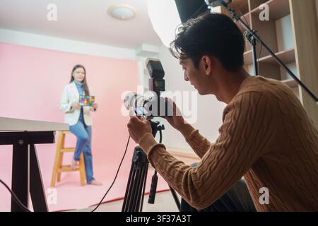 Asian photographer taking photos of female model in professional studio Stock Photo