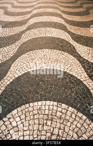 Portuguese calcada pavement displaying a classic wave mosaic pattern and cobblestone texture Stock Photo