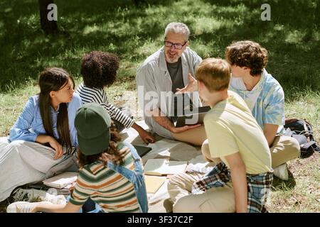 Diverse Teen Students Collaborating with Teacher in Outdoor Lesson Stock Photo