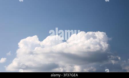 Large fluffy white cumulus clouds float calmly in bright clear blue sky during sunny summer afternoon, light gentle breeze pristine nature beautiful a Stock Photo
