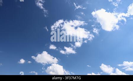 Beautiful blue sky filled with white fluffy clouds on bright sunny day creates peaceful natural background full of light freedom and high atmosphere, Stock Photo