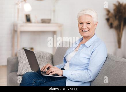 Freelance Jobs For Seniors. Happy Elderly Woman Working On Laptop At Home Stock Photo