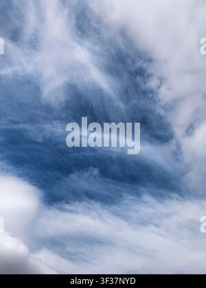 Elegant layered cirrus clouds sweeping across a vivid blue sky. Natural atmospheric background with flowing cloud textures and dramatic visual pattern Stock Photo
