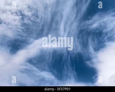 Wide scenic view of flowing cirrus clouds mixed with scattered cumulus formations over a bright blue summer sky. Dramatic natural cloudscape backgroun Stock Photo