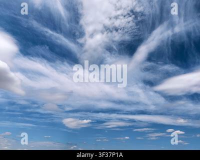 Large layered clouds stretching across a bright blue sky with scattered cumulus formations. Scenic weather background with impressive atmospheric text Stock Photo