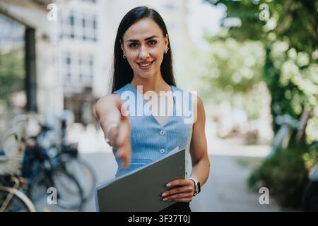 Professional woman offering a handshake outdoors during a business meeting and recruitment conversation Stock Photo