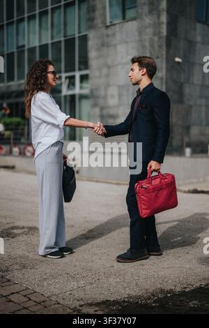 Business meeting handshake between two professionals outside a modern office building during a greeting Stock Photo
