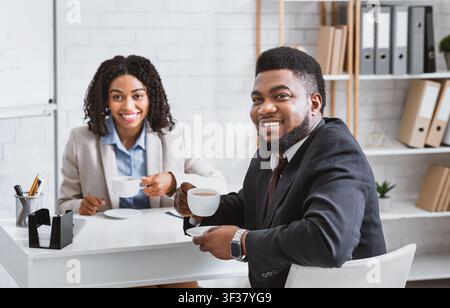 Smiling personnel manager and successful vacancy candidate drinking coffee during job interview at office Stock Photo