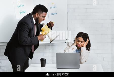 Angry boss with megaphone screaming at employee in office Stock Photo