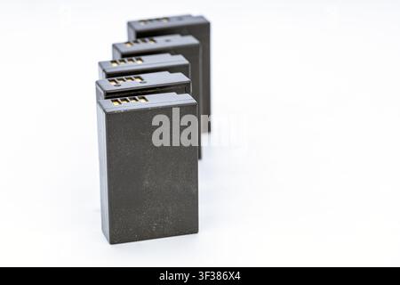 Professional studio photograph of four identical black rechargeable lithium-ion digital camera batteries arranged in a diagonal row on a clean white b Stock Photo