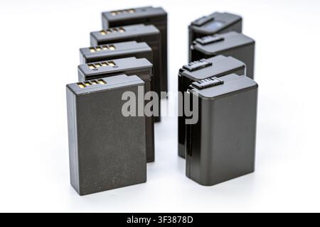 Multiple rechargeable lithium-ion batteries designed for digital cameras stand upright in two clusters on a pristine white studio background. Stock Photo