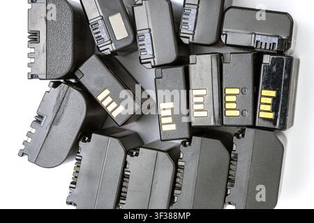 Multiple black rechargeable lithium-ion battery packs designed for digital cameras and camcorders are piled together on a clean white surface. Stock Photo