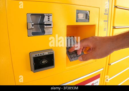 User interacting with a yellow Paket24 terminal, entering a PIN on the Verifone keypad for package retrieval or payment in Rijeka, Croatia. Stock Photo