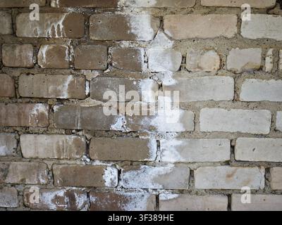 Rough textured wall displays variations in brick color and wear from exposure to elements in an outdoor setting during daylight. Stock Photo
