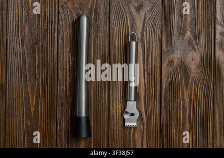 Top view flat lay of professional bartender equipment featuring a metal cocktail muddler and a citrus zester peeler with channel knife placed vertical Stock Photo