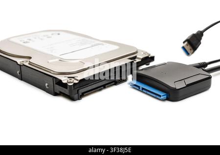 A studio close-up shot of an internal 3.5-inch hard disk drive (HDD) next to a black SATA to USB adapter cable interface. The image clearly demonstrat Stock Photo