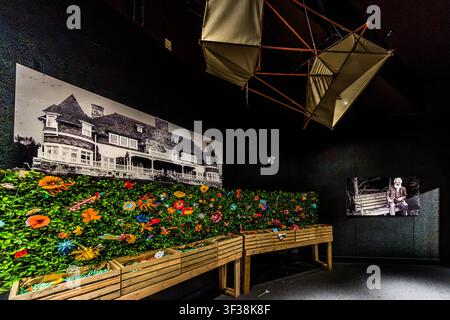 A room installation featuring a historical photograph of Bell’s Beinn Bhreagh estate, an artificial floral hedge and a screen showing historical film footage of an ageing Alexander Graham Bell sitting on a bench forms part of the exhibition at the Alexander Graham Bell National Historic Site on Chebucto Street in Baddeck, Nova Scotia, Canada. Hanging above it is a replica of a tetrahedral cell kite from Bell’s later flight experiments Stock Photo