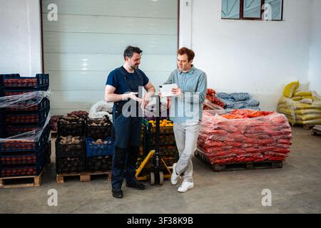 Warehouse workers discussing logistics and inventory on digital tablet Stock Photo