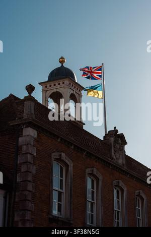 Seven Sisters, Hastings – 2026.03.28 – Historic brick building rooftop with two flags waving against clear sky. Stock Photo
