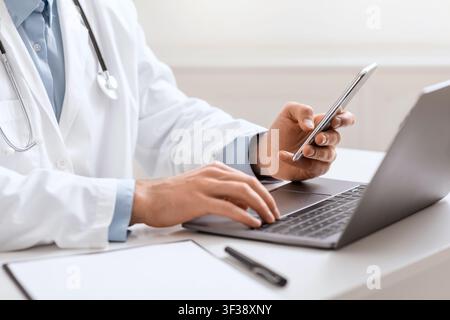 Doctor working with smartphone and laptop , close up Stock Photo
