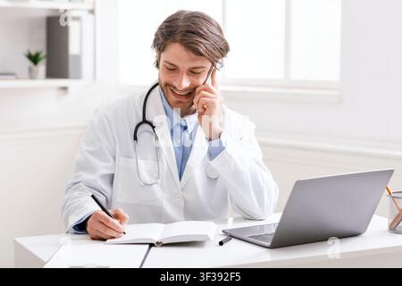 Doctor talking with patient via phone and taking notes Stock Photo