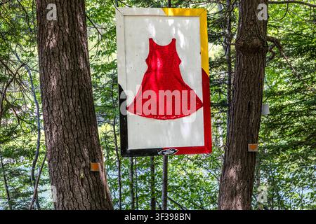 A sign mounted on a tree trunk on the Goat Island Trail in the Eskasoni First Nation, Nova Scotia, Canada – part of the Red Dress Day art installation commemorating missing and murdered Indigenous women, girls and Two-Spirit people along the circular trail Stock Photo