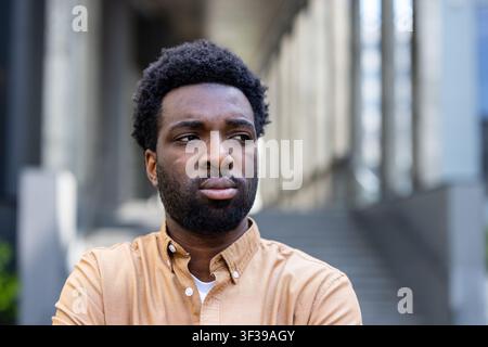 Young african american man standing outdoors in an urban setting, deeply thinking and looking away with a serious expression, conveying contemplation and focus on future challenges Stock Photo